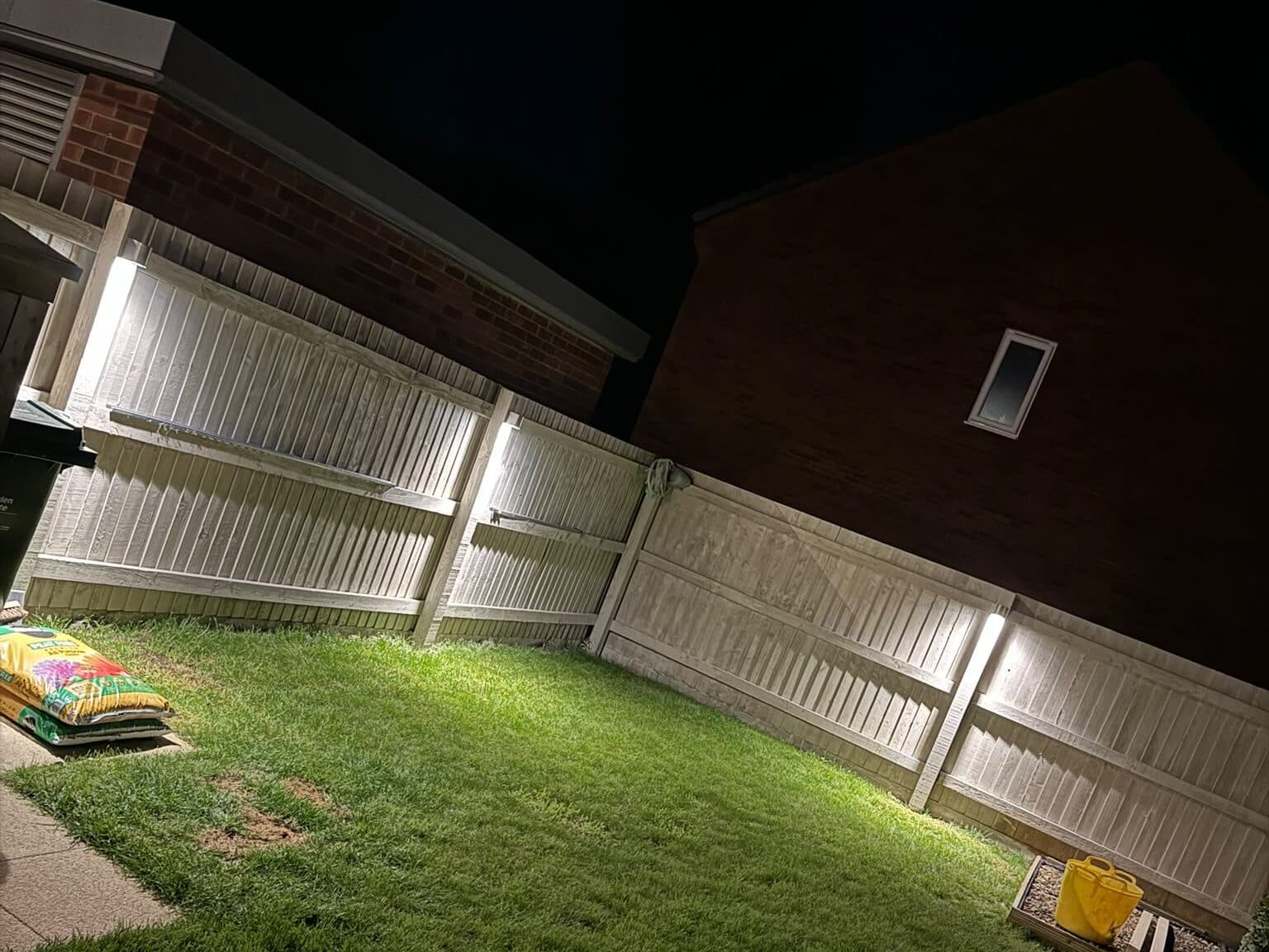 Garden at night with lights fitted along the fence posts