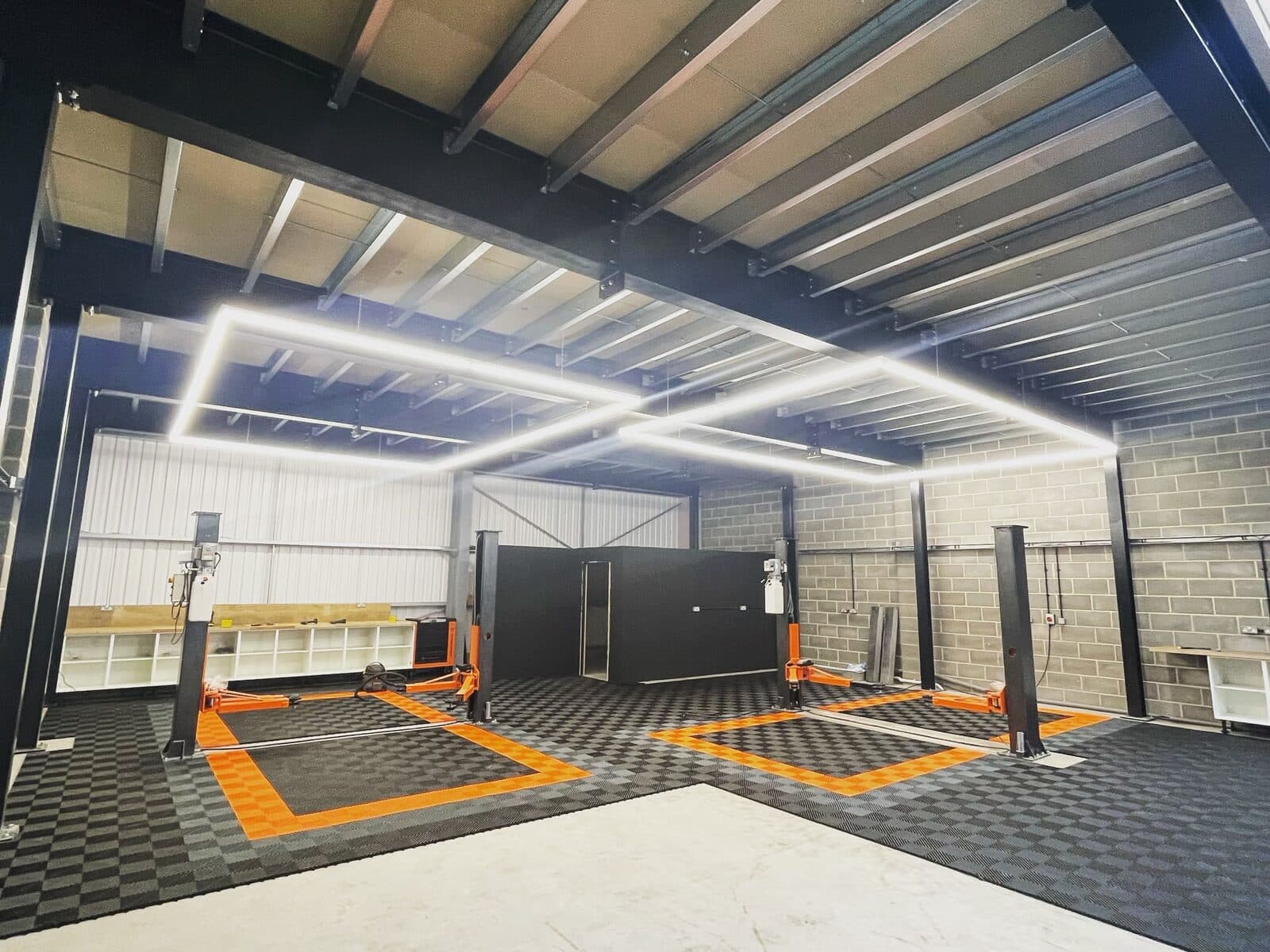 Workshop with long LED light lines across the ceiling over the car lifts